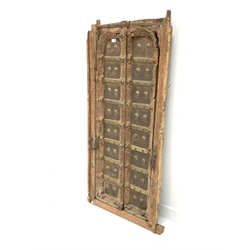  Pair northern Indian teak and metal bound doors, with carved detail and decorative brass studding, in original frame, 70cm x 138cm  