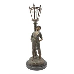 French patinated spelter table lamp modelled as a boy leaning against a street lamp, on circular marble plinth, H54cm overall