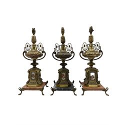 Pair of Continental rococo style gilt metal ornate table lamps with foliate decoration featuring painted porcelain scenes on marble bases and gilt feet together with another (3)