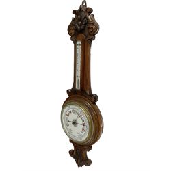 Early 20th century carved oak aneroid barometer - profusely carved top and base with a mercury thermometer and porcelain register recording barometric air pressure from 26 to 31 inches, with a steel indicating hand and brass recording hand within a brass bezel and flat glass.