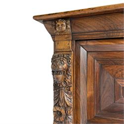 17th century Dutch rosewood and oak ‘Zeeuwse Kast’ or cupboard, projecting cornice carved with three putti masks, the uprights carved with lion masks over ribbons, flower heads and foliage, enclosed by four geometric panelled doors, lower central upright carved with flower head over foliate ribbon with bird among foliage, the escutcheon hidden by swivel berry carved cover, interior fitted with shelves, two drawers and shallow hinged cupboard, on two large turned and ebonised feet