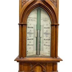 A Victorian boxwood cistern tube stick barometer manufactured by Nagretti & Zambria, London, circa 1860 in an oak “Gothic” revival case, with a fleur-de-Lis carved pediment on a projecting cornice, the pediment supported by carved columns and pendants with carved spandrels flanking a central double register, with weather predictions and barometric air pressure from 27 to 31 inches, twin vernier scale on either side of the mercury tube recording “today's” and “yesterdays” air pressure, dial inscribed ”Neggretti & Zambria instrument makers to her majesty, 1 Hatton Gardens, 50 Cornhill & 122 Regent Street” rectangular trunk with canted corners, two carved vernier setting discs above a boxed scale mercury thermometer measuring the temperature in degrees fahrenheit and centigrade, corresponding rectangular carved plinth to the cistern cover.