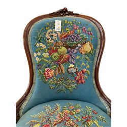 Victorian mahogany framed nursing chair, applied rose carved cresting rail, back and sprung seat upholstered in floral tapestry fabric, raised on turned lobe carved supports with ceramic castors