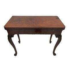Early 19th century figured mahogany card table, the fold open top revealing circular baise inset, the double hinge extending base with oak sliding support, raised on cabriole supports with c-scroll and cartouche carved knees with extending foliate decoration