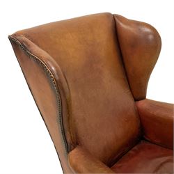Georgian design wingback armchair, high back over down-scrolled arms, upholstered in tan leather with studwork border, raised on cabriole supports with shell moulded knees