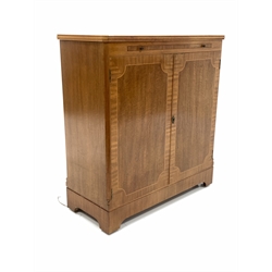 Mid 20th century mahogany illuminated cocktail cabinet, the cross banded and boxwood strung top with inset plate glass over mirrored slide, glazed sliding doors opposite two cupboard doors under, enclosing three shelves, one with bottle recesses, raised on castors 