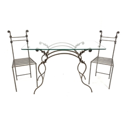 Blacksmith made wrought metal garden suite, comprising a table with glass top raised on spiralled, scrolled and serpentine rod base, together with a pair of matching chairs 