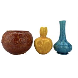 Burmantofts Faience oxblood-glaze jardiniere, decorated in low relief with panels of flowers, model no. 549, ochre glaze dimple vase, model no. 990 and turquoise bottle vase no. 1612, all having impressed factory marks beneath, H26cm (3)