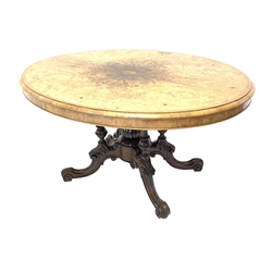 Victorian inlaid walnut oval loo table, the quarter sawn veneered and moulded top raised on four column supports with central finial on four carved scrolling feet, ceramic castors