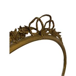Gilt framed oval wall mirror with floral and foliate decoration, surmounted with a shell pediment 