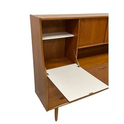 Jentique - mid-20th century teak highboard or wall unit, the top section fitted with drinks cupboard enclosed by fall-front door, two sliding doors concealing shelf, lower section fitted with three graduating drawers and two cupboard doors, raised on tapering supports