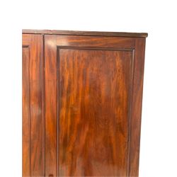 Large George III mahogany wardrobe, two panelled doors enclosing handing rail and five sliding trays, over deep single drawer with brass pull handles, on plinth base