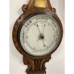 An Edwardian English solid oak carved hall barometer in a scroll shaped carved case with applied leaf carving, compensated Aneroid movement, seven-inch register measuring barometric air pressure from twenty-six to thirty-one inches, weather predictions written in Roman capitals with a blue steel indicating hand and recording hand, brass bezel with flat bevelled glass, mercury thermometer enclosed in a glazed rectangular box recording temperature in degrees Fahrenheit and Celsius, brass presentation plaque dated 1910.

With a 20th century wall clock with a Smiths going barrel “Empire” movement and platform escapement, 11” metal dial with roman numerals and minute track, steel spade hands, fast slow regulation, with a spun bezel mounted on an oak effect dial bezel and wooden movement case.
