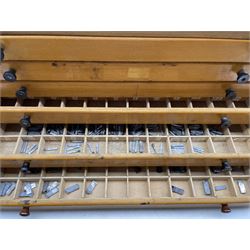 A six drawer printers chest containing a quantity of metal stamps/ matrices, H25cm, W51cm, D25cm