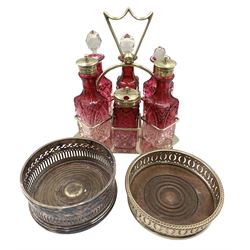 Early 20th century silver-plated cruet set with six cranberry glass bottles, together with a pair of silver-plated bottle coasters (3)