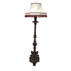 Antique mahogany standard lamp, turned column profusely carved with leaves, flutes and lobes, over a trefoil base with further carvings of scrolled acanthus leaves and cartouches, raised on three paw supports, with a decorative lampshade 