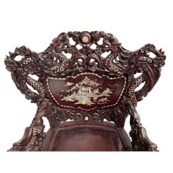 Pair early 20th century Chinese hardwood armchairs, the backs pierced and heavily carved with dragons and trailing flower heads, the seat backs with mother of pearl inlays depicting warriors with horses and traditional landscapes, the arms carved as a dragon with agape mouth and mother of pearl inlaid scales, scaled fish feet terminating to masks