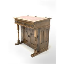 Old Charm - 20th century oak writing desk, the sloped top with inset tooled red leather writing surface lifting to reveal storage well, over lunette and floral carved frieze, two turned pilasters and two panelled doors, raised on sledge supports W94cm, D59cm, H91cm