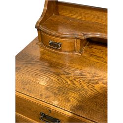 Early 20th century oak dressing chest, arched bevel edged swing mirror over open shelf and two trinket drawers, two short and two long drawers to base, raised on stile supports W107cm