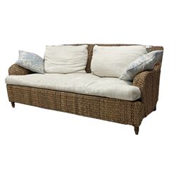 20th century two seat woven seagrass sofa, Howard shape with downswept arms, with cream upholstered loose seat and back cushions, on turned feet