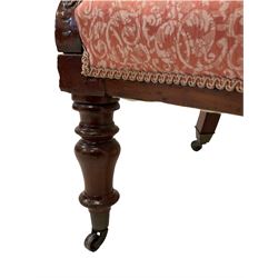 19th century mahogany armchair, upholstered in buttoned pink foliate patterned fabric, scrolled arm terminals with carved decoration, raised on turned supports with castors