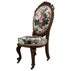 Victorian walnut nursing chair, pierced scrolling pediment, upholstered in Sanderson's 'Chelsea' floral pattern fabric, on scroll carved cabriole supports with brass castors