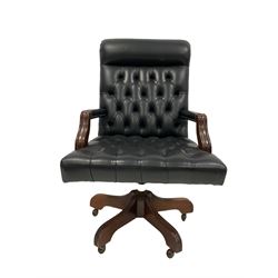 Mahogany swivelling and adjustable desk chair, upholstered in buttoned black leather 