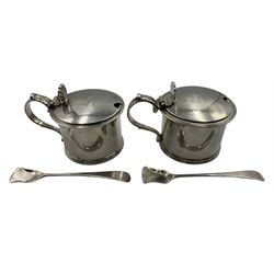 Pair of George V silver mustards, of cylindrical form with scroll handles and shell form thumbpieces, the hinged covers with engraved family crest, blue glass liners, by Stokes & Ireland Ltd 1920, together with a pair of George III silver salt scoops by  Christian Ker Reid, Newcastle 