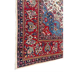 Large Persian Kashan carpet, the pale ground field decorated with shaped medallion and bunches of trailing flower heads and foliage, light blue and red ground spandrels with floral design, seven band border with overall floral design, the main band decorated with stylised plant motifs and trailing branch