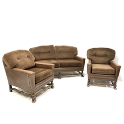 Early 20th century three piece suite, comprising a two seat sofa upholstered in studded leather with squab cushions, raised on turned and splayed block supports united by shaped stretchers, (W155cm) and a pair of matching armchairs (W72cm)