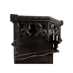 18th century and later Gothic Revival walnut and oak narrow dresser, the projecting pierced tracery canopy with egg and dart carved edge decorated with applied roses, over a three-tier plate rack, the base with a rectangular walnut top with feather banding, the edge carved with repeating anthemion decoration, the single cupboard door applied with gothic tracery and acanthus leaf moulded edge, enclosing two shelves