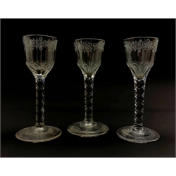Set of three 18th century wine glasses, the ovoid bowls engraved with flower sprigs on faceted stems and conical feet, H15cm 