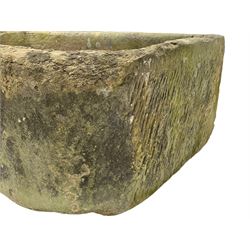 Large weathered sandstone D-shaped trough, roughly tooled exterior and deeply hewn centre
