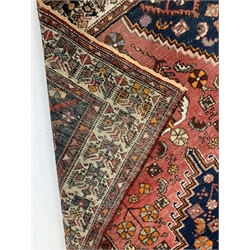 Persian red ground rug, with lozenge medallion on field decorated with stylised geometric floral design, enclosed by border, 200cm x 134cm
