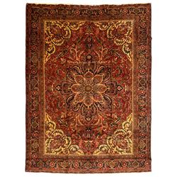 Persian Meshed crimson ground carpet, large central medallion decorated with stylised plant and leaf motifs, the field with overall floral design with trailing branches, shaped spandrels decorated with further floral motifs, repeating border with guard bands