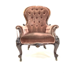 Victorian mahogany armchair, upholstered in deep buttoned velvet, with scroll and floral carved arm terminals over cabriole supports and brass castors, 