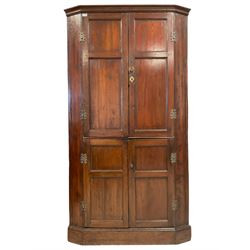 George III stained pine double corner cupboard, the projecting cavetto cornice over four panelled cupboard doors, the top section concealing a fitted interior with seven oak spice drawers and two shaped shelves, the lower section with single shelf, the interior painted a pale teal, raised on plinth base