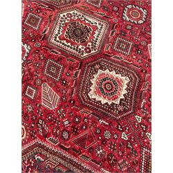 Old Persian rug, red and blue ground with triple lozenge medallions, the field decorated all-over with small stylised motifs, the outer border decorated with Boteh motifs