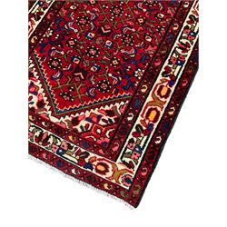 Persian Hamadan runner, red ground field with central stepped lozenge, decorated with larger Herati motifs, ivory band border decorated with geometric patterns