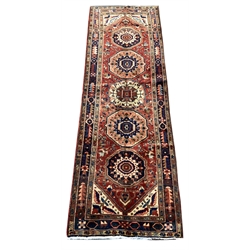 Unusual Persian runner rug, red ground field with five medallions and decorated with stylised flower heads, floral spandrels, guarded repeating border, 335cm x 110cm