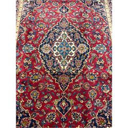 Persian Kashan red ground rug, blue central medallion and spandrels with floral design, the field decorated with scrolling branch and stylised plant motifs, repeating border with guards