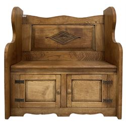 Oak and elm settle, the panelled back with carved lozenge over seat and two cupboard doors, raised on panel end supports 