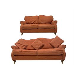 Traditional three seat sofa, scrolled arms, upholstered in red lozenge patterned fabric, raised on turned feet with brass castors (W180cm D90cm H77cm); with matching two seat sofa (W160cm)