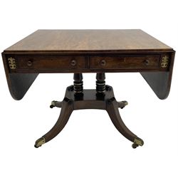 Regency rosewood and brass inlaid sofa table, drop leaf rectangular top with rounded corners, fitted with two drawers and two opposing false drawers, turned twin pillars on platform, splayed supports with foliate cast brass cups and castors