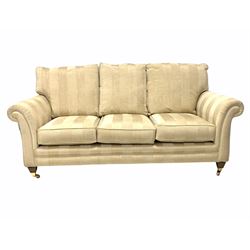 Traditional three seat sofa, upholstered in stripped ivory fabric, raised on square tapered supports with brass cup castors (W200cm) together with a matching arm chair (W100cm)