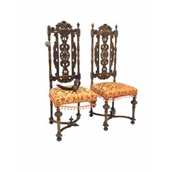 Pair of Victorian oak high back hall chairs, the back profusely carved with scrolls and foliate, upholstered seats, raised on turned supports united by 'X' stretcher W47cm