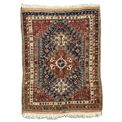 Antique Persian Quashqai maroon ground rug, the interlocking geometric medallion with two flanking roods surrounded by an indigo field with stylised plant motifs, the guarded border with repeating geometric patterns