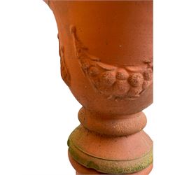 Pair of terracotta garden planters on pedestals, urn-shaped planters decorated with festoons, on twist pedestals with circular moulded footed base