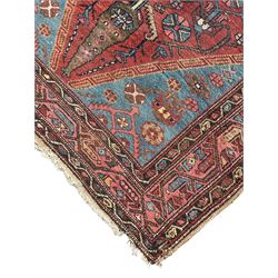 Persian Hamadan rug, red ground with blue central medallion, decorated with stylised flower head and plant motifs, triple band border with repeating geometric design