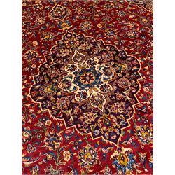 Persian Kashan red ground carpet, the central floral pole medallion within a busy field filled with with scrolling foliate decoration and stylised palmettes, with matching spandrels, the guarded border with interlaced scrolling floral motifs